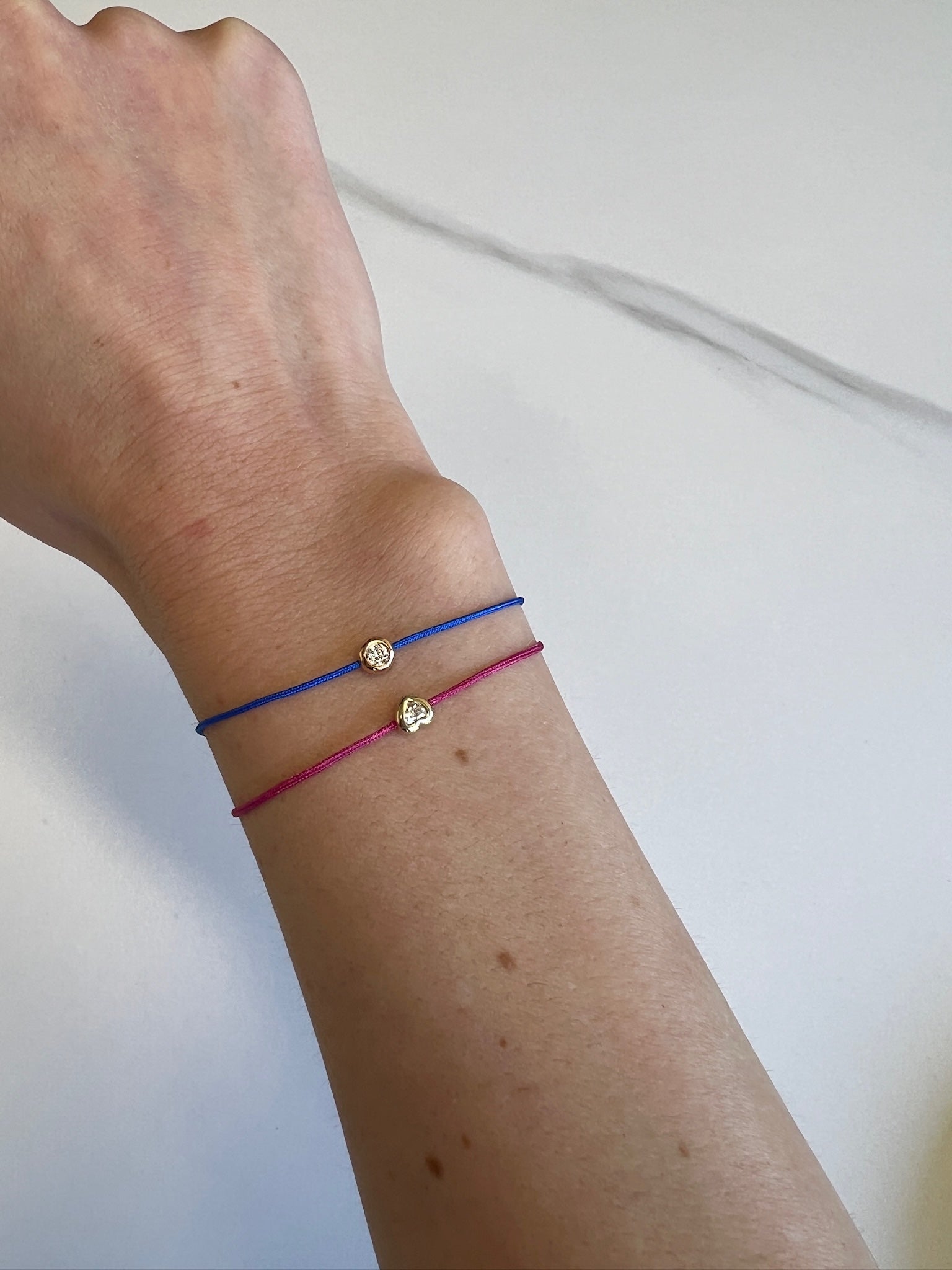 The Cobalt Blue round Diamond Cord Bracelet from Janet Heller Fine Jewelry is crafted in 14KT gold.  The string bracelet features a single diamond in a bezel setting.  The bracelet can be stacked or worn alone.