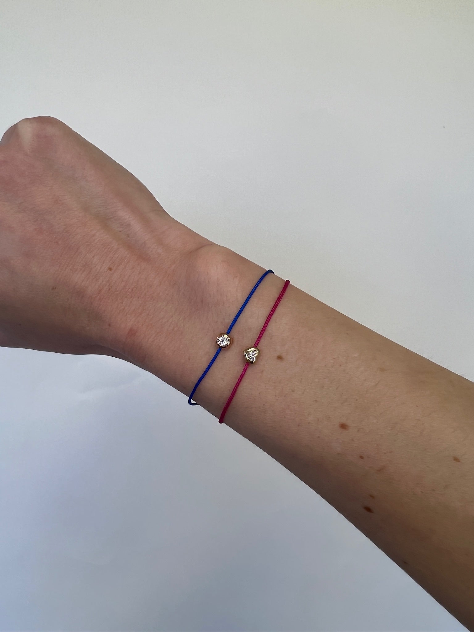 The Cobalt Blue Round Diamond Cord Bracelet from Janet Heller Fine Jewelry is crafted in 14KT gold. The string bracelet features a single diamond in a bezel setting with an adjustable chain. The bracelet can be stacked or worn alone.