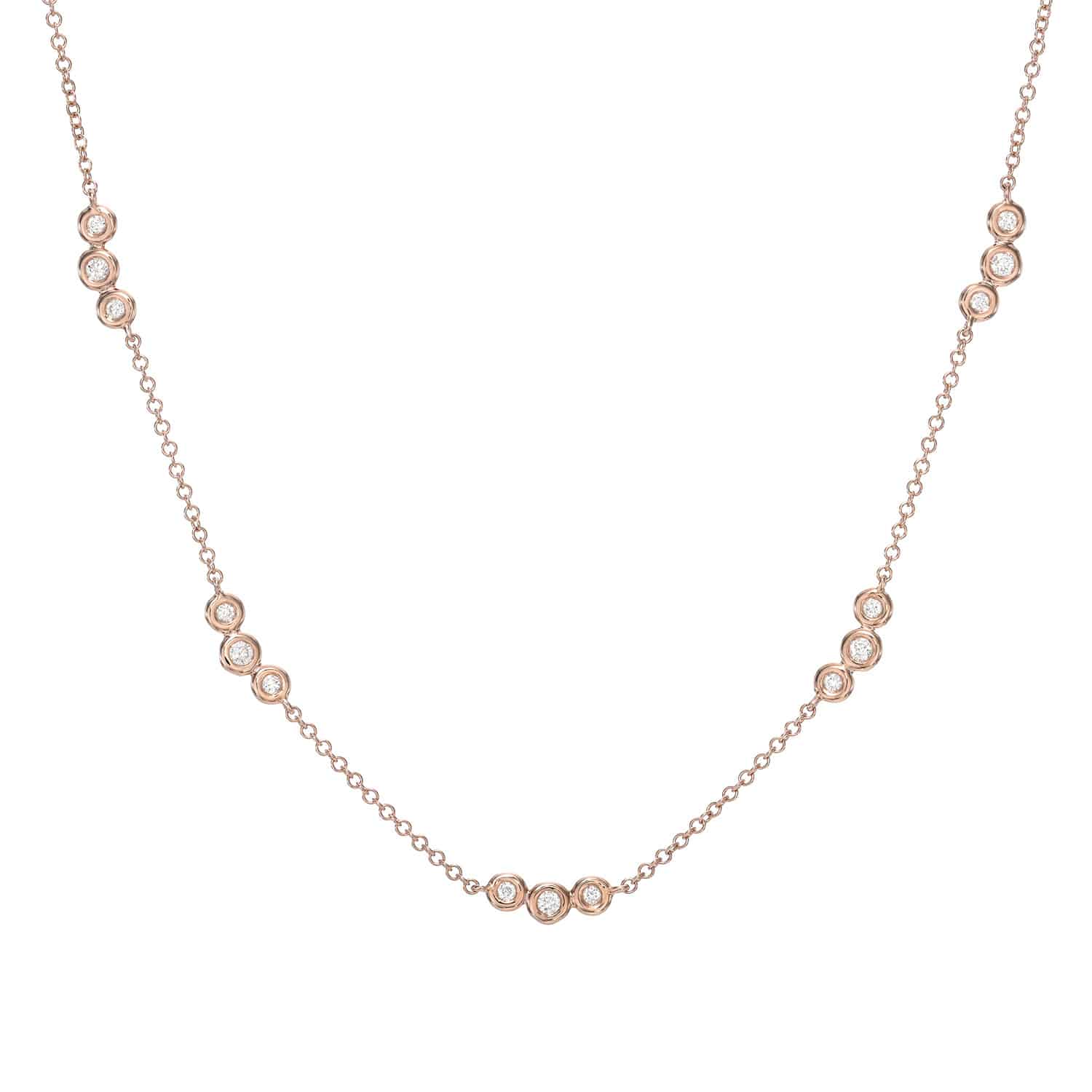 The Bezel Diamond Trio Station Necklace by Janet Heller Fine Jewelry is crafted in 14KT gold. It features a gold chain with clusters of three small, round diamonds set in circular bezels linked by delicate chains. The necklace can be worn alone or layered with other necklaces.