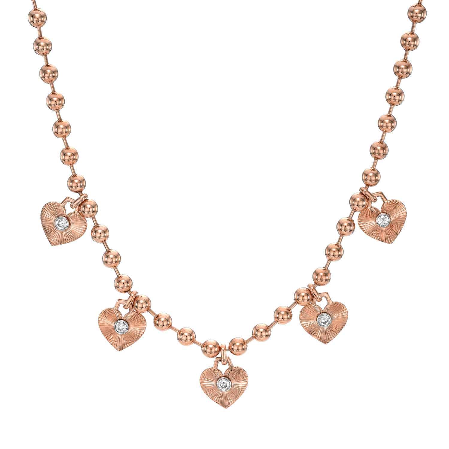 The Diamond Heart Scarlett Necklace is an exquisite gold piece featuring spherical beads and five heart-shaped pendants, each with a diamond-like stone. Its a unique item perfect for customization to suit your style.