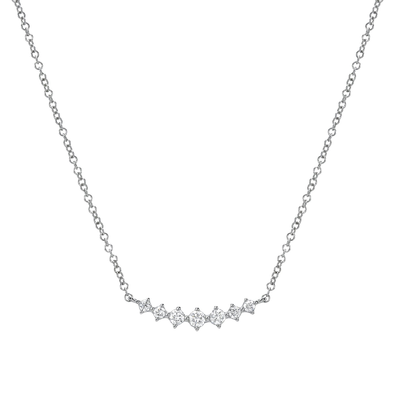 The Graduating U Shaped Diamond Necklace by Janet Heller Fine Jewelry has a thin silver chain with clustered small diamonds in a subtle wave pattern. The diamonds brilliantly catch the light, adding sparkle and showcasing fine jewelry craftsmanship.