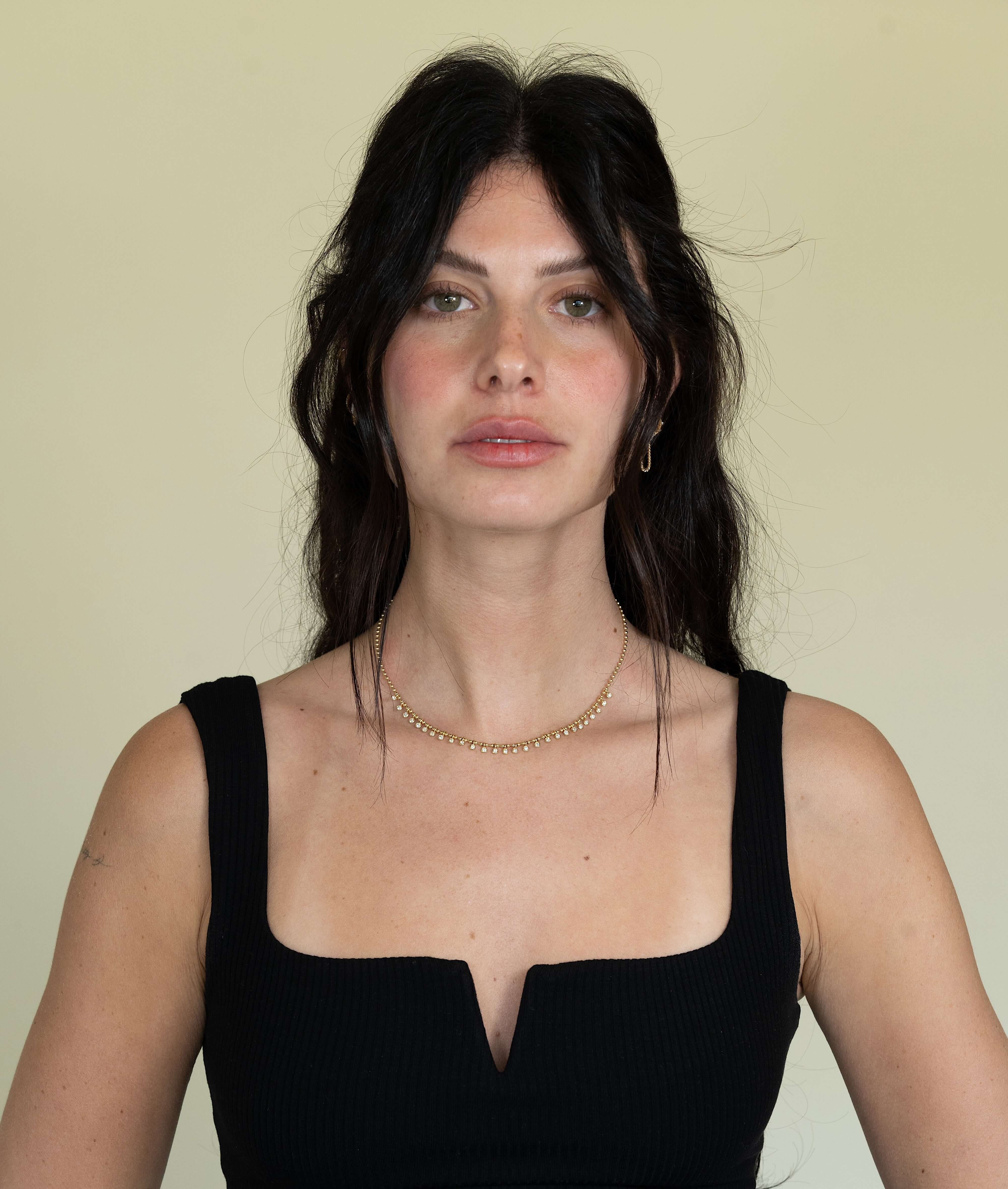 The Diamond Eisley Necklace from Janet Heller Fine Jewelry is crafted in 14KT gold. It features a chain of gold beads with dangling round diamonds. The necklace can be worn on its own or layered with other necklaces.