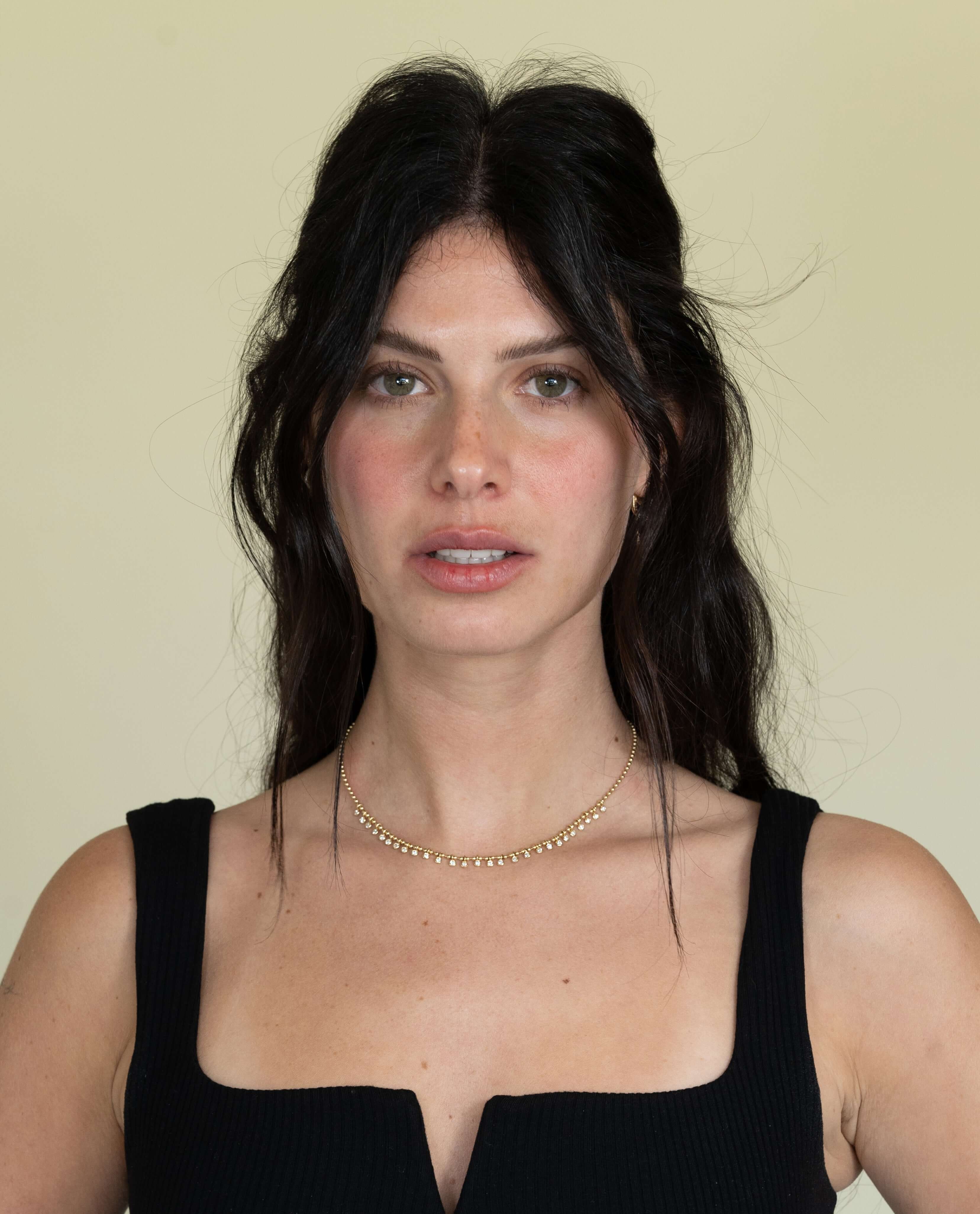 The Diamond Eisley Necklace from Janet Heller Fine Jewelry is crafted in 14KT gold. It features a chain of gold beads with dangling round diamonds. The necklace can be worn on its own or layered with other necklaces.