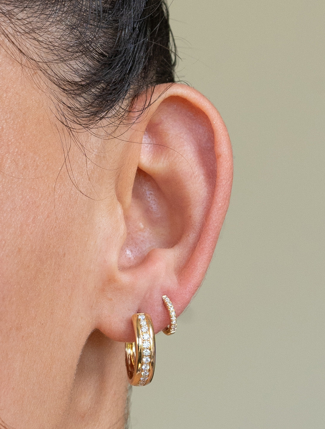 The Diamond Sutton Hoops from Janet Heller Fine Jewelry are crafted in 14KT gold. The hoops feature two plain bands surrounding a row of diamonds. The hoops can be worn alone or layered along with ear with other earrings.