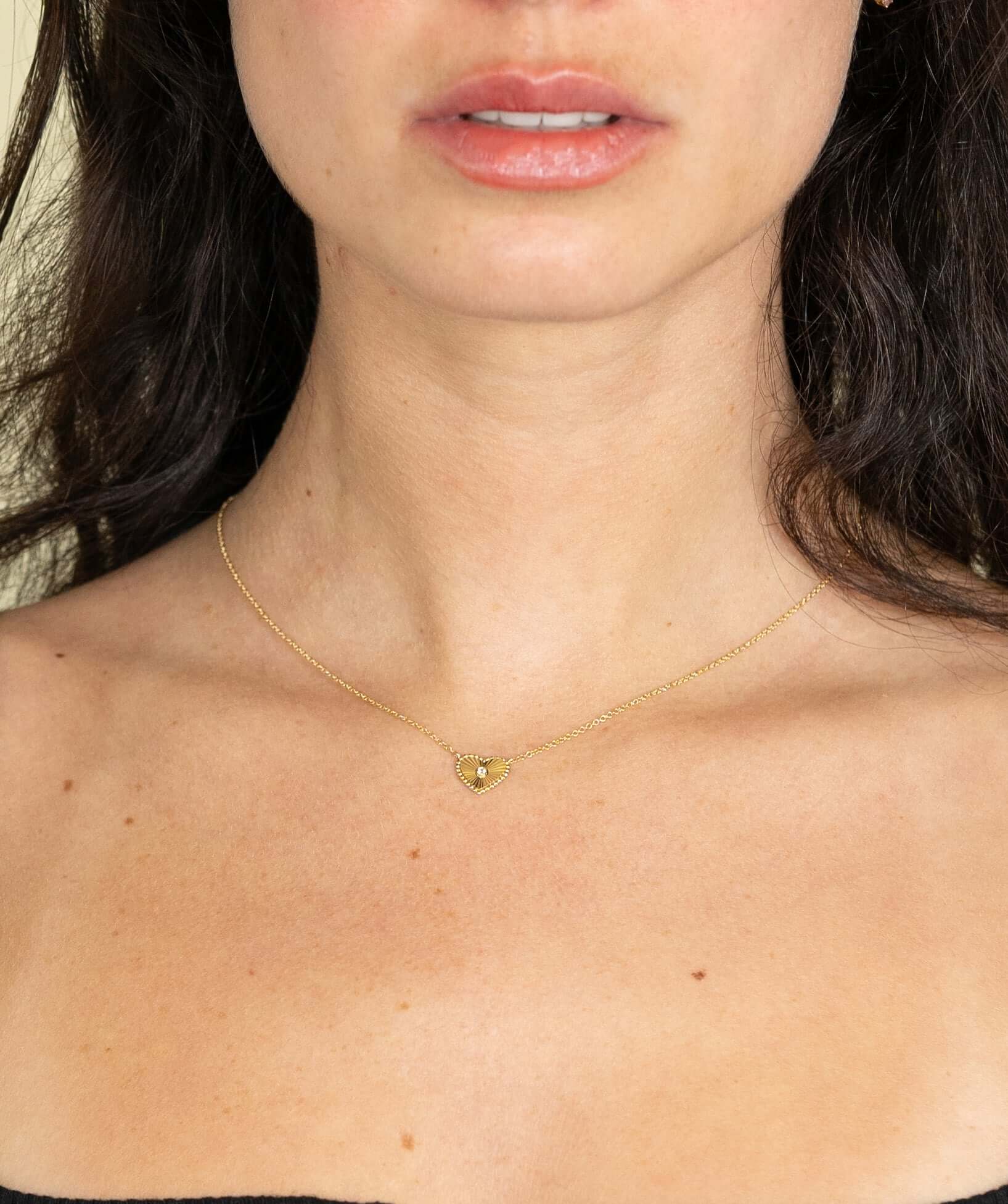 The Mini Diamond Ridge Heart Necklace from Janet Heller Fine Jewelry is crafted in 14KT gold.  The necklace showcases a delicate chain with a ribbed heart pendant, set with a single diamond in the center. The 18" necklace can be worn on its own or layered.