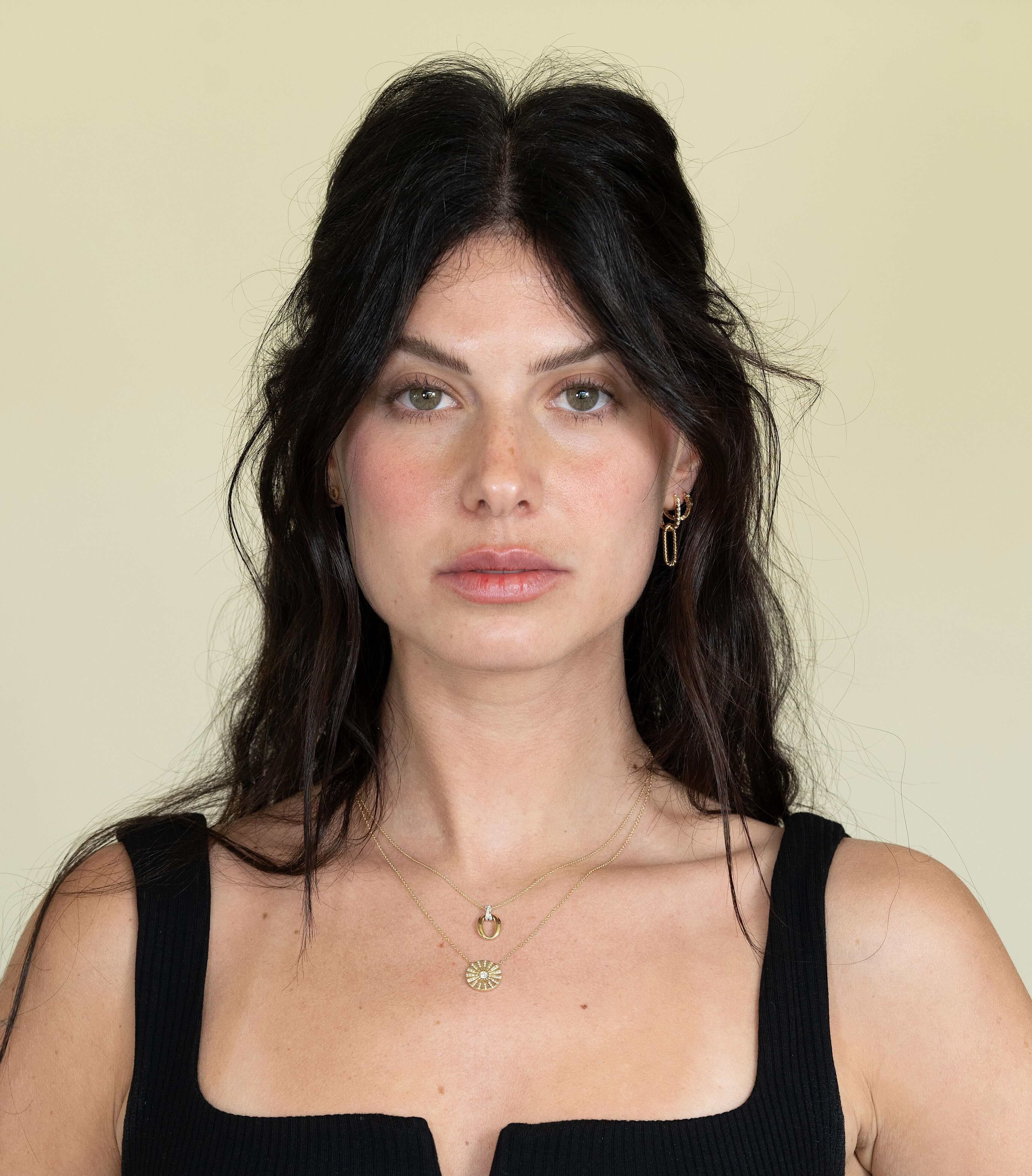The Del Sol Diamond Circle Necklace by Janet Heller Fine Jewelry is crafted in 14KT gold. The pendant showcases a diamond starburst pattern with a round center diamond. The necklace can be worn alone or layered with other necklaces and chains.