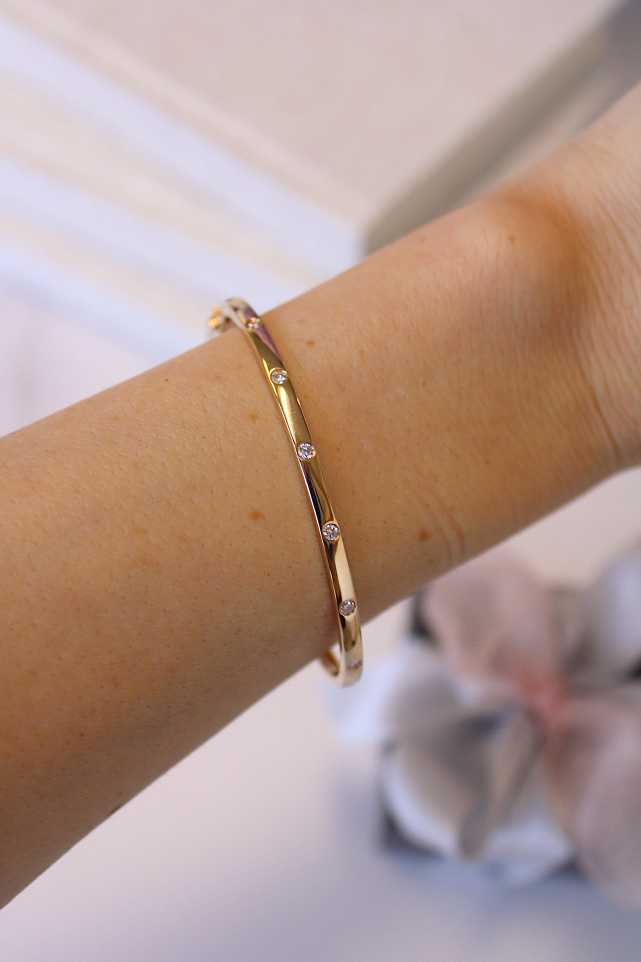 The Diamond Avery Bangle from Janet Heller Fine Jewelry is crafted in 14KT gold and is embellished with seven round diamonds. The bangle can be worn on its own or stacked with other bracelets.