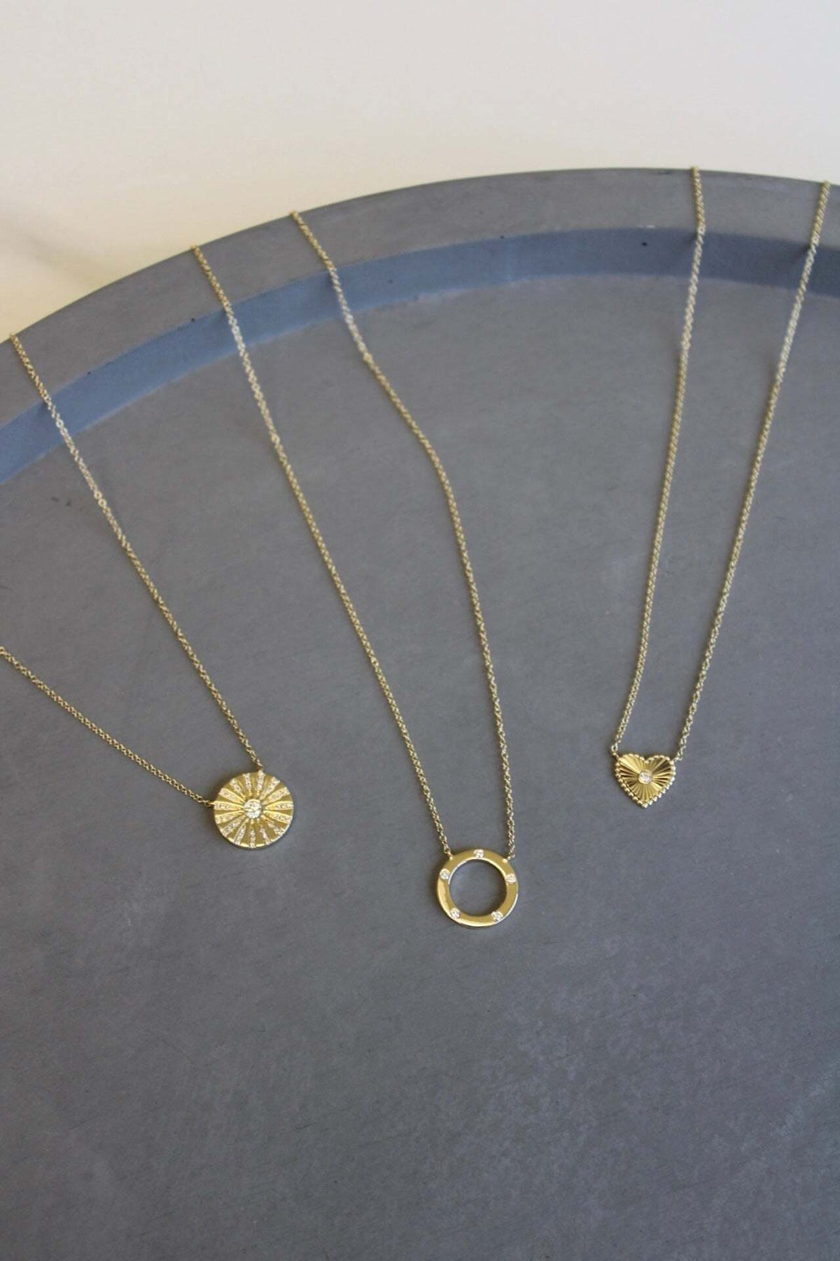 The Mini Diamond Ridge Heart Necklace from Janet Heller Fine Jewelry is crafted in 14KT gold. The Necklace features a sunburst pendant with a center diamond and a beaded edge. The necklace can be worn alone or layered with other chains and necklaces.