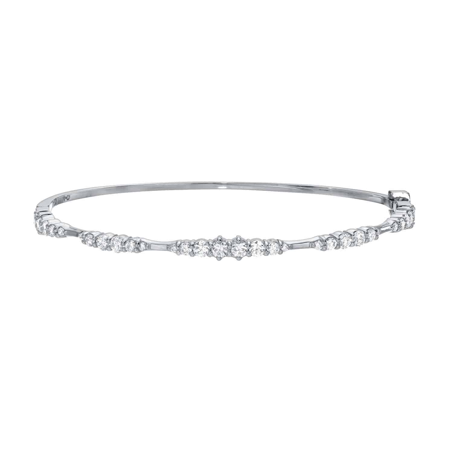 The Graduating Diamond Bangle from Janet Heller Fine Jewelry is a silver bracelet featuring a row of evenly spaced, sparkling diamonds. It showcases a smooth finish and an elegant, minimalist design.