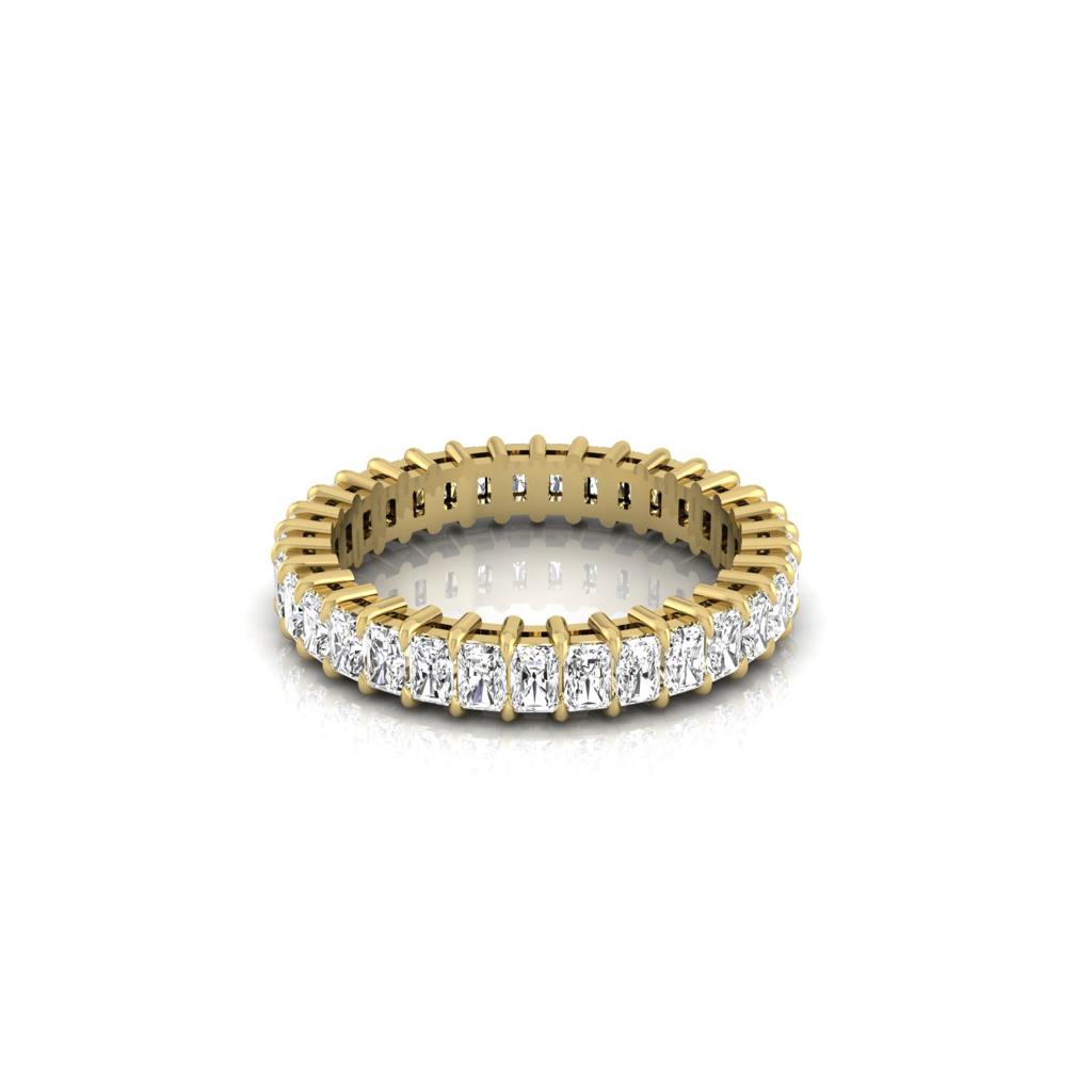 The Full Lab Grown Diamond Eternity Ring, crafted in 18KT gold with radiant round diamonds of F Color and VS Clarity encircling it entirely, elegantly rests on a white reflective surface, exuding timeless beauty.