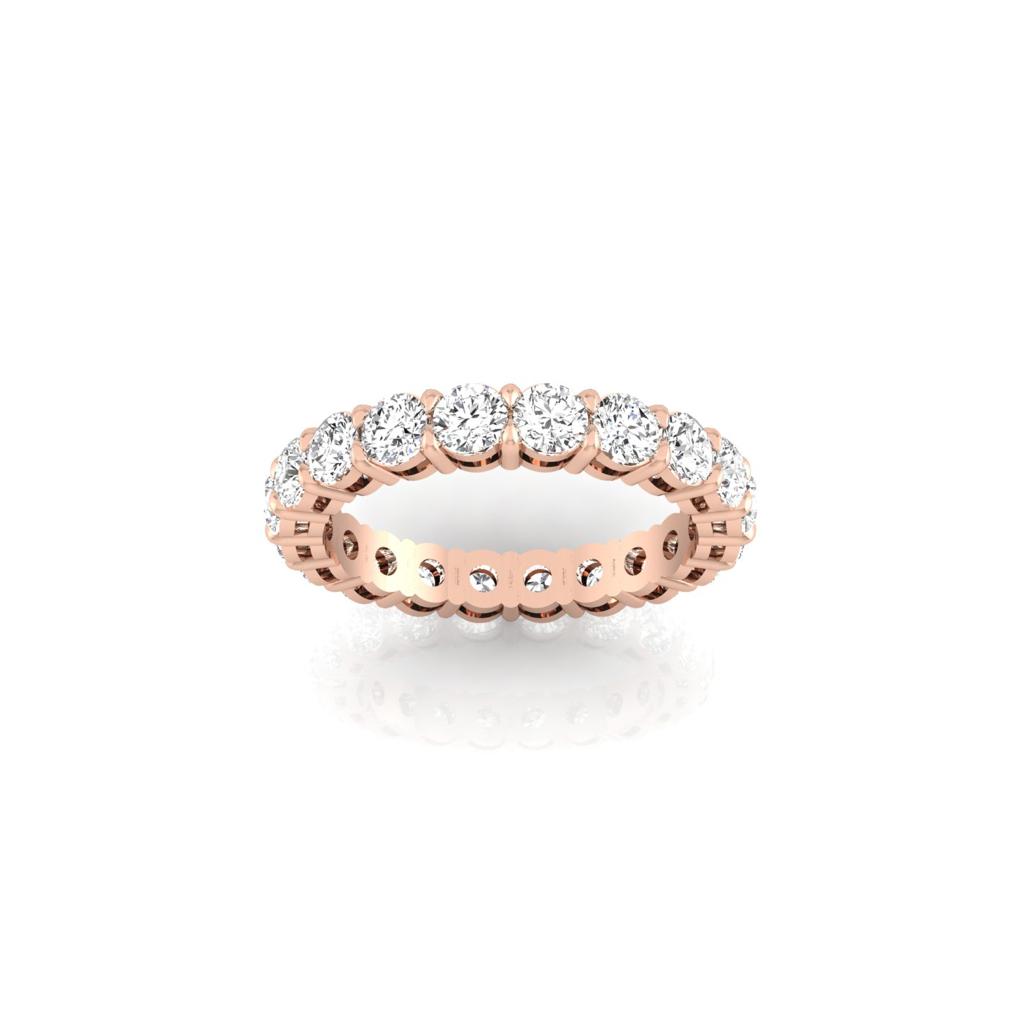 The Full Lab Grown Diamond Eternity Ring in 18KT rose gold, featuring F Color VS Clarity round diamonds, glistens elegantly on a reflective white surface.