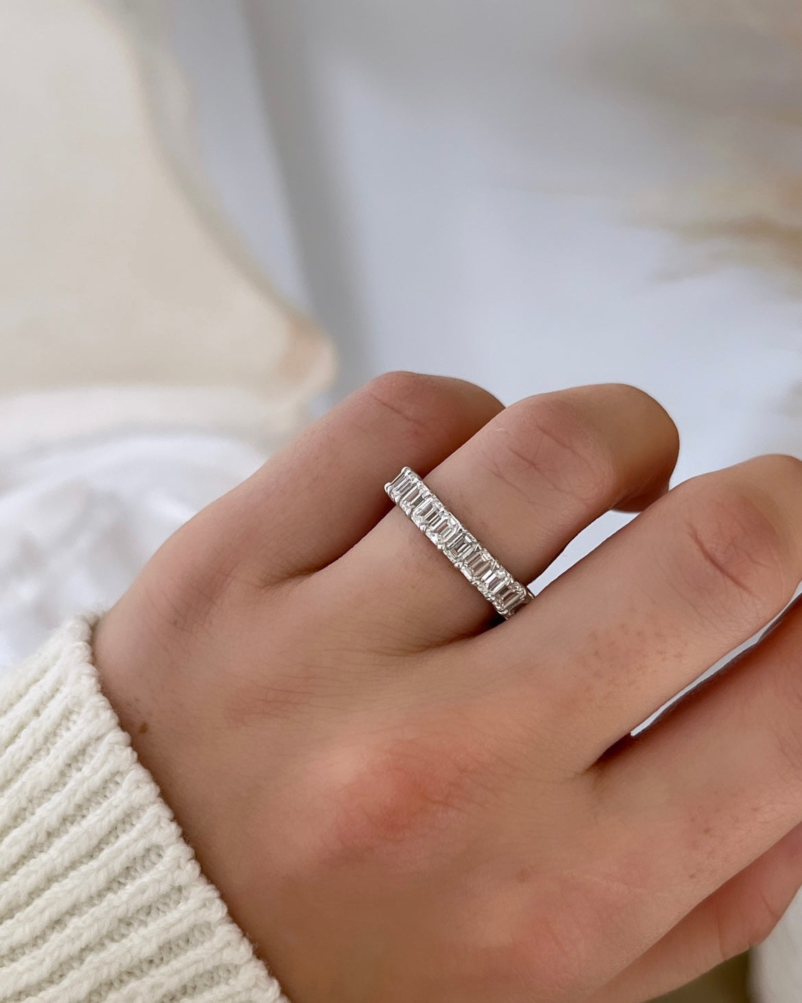 The Full Lab Grown Diamond Eternity Ring from Janet Heller Fine Jewelry, crafted in 18KT gold, features evenly spaced diamonds offered in various shapes and custom carat weights. The color of the diamonds is F and the clarity is VS. This is the perfect wedding band to be worn alone or stacked with your engagement ring.