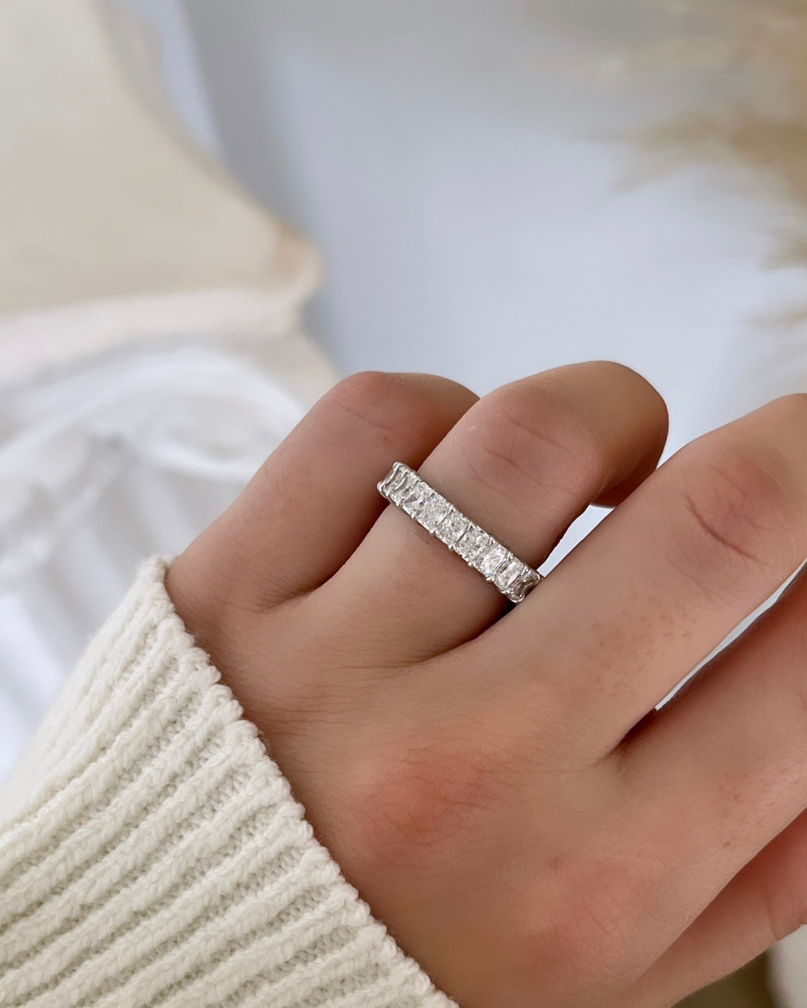 The Full Lab Grown Diamond Eternity Ring from Janet Heller Fine Jewelry, crafted in 18KT gold, features evenly spaced diamonds offered in various shapes and custom carat weights. The color of the diamonds is F and the clarity is VS. This is the perfect wedding band to be worn alone or stacked with your engagement ring.