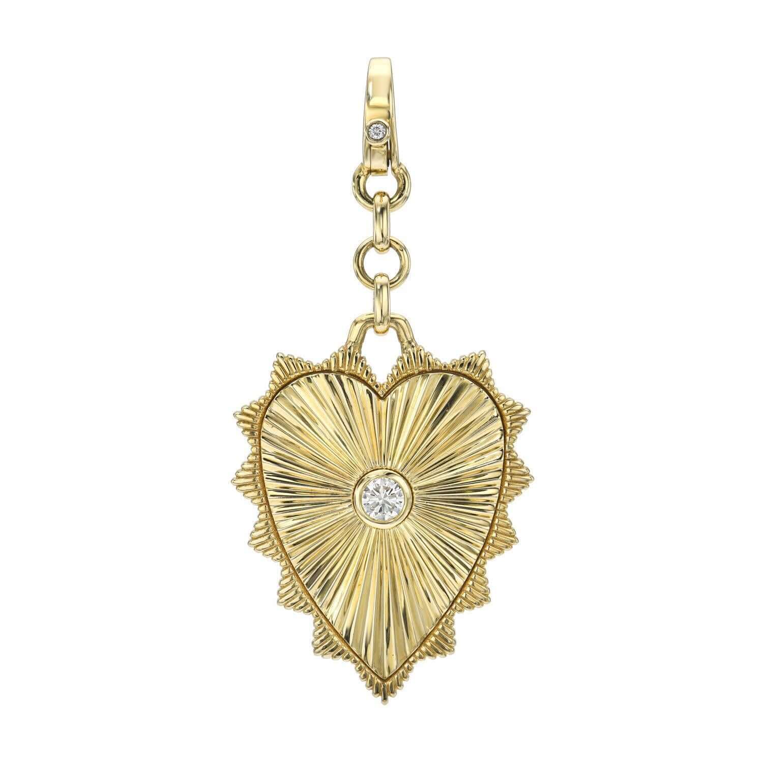 The Diamond Sydney Charm by Janet Heller Fine Jewelry is an exquisite gold heart-shaped pendant with a textured surface and central round diamond. It features a decorative border and hangs elegantly from a gold link charm adorned with an additional small diamond for extra sparkle.
