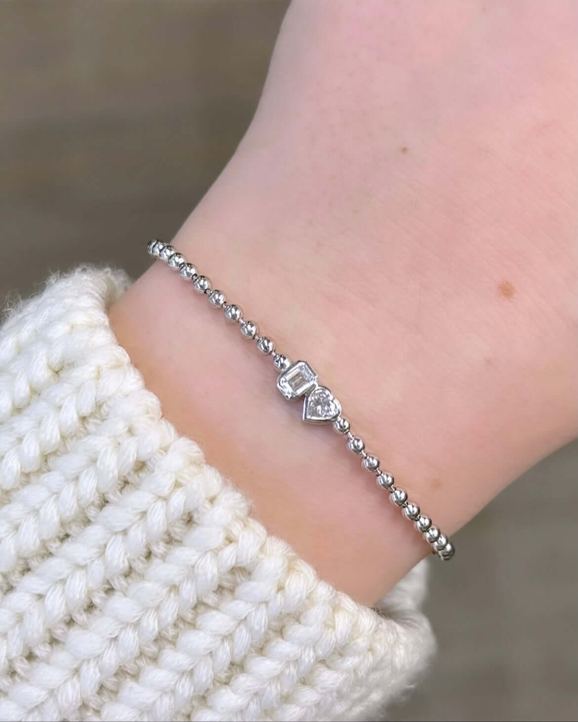 The Emerald & Heart Toi Et Moi Bracelet from Janet Heller Fine Jewelry, is crafted in 14KT gold and features heart and emerald-cut diamonds. The diamonds are 0.15 carats each and are in bezel settings. The bracelet can be worn on its own or stacked with others.