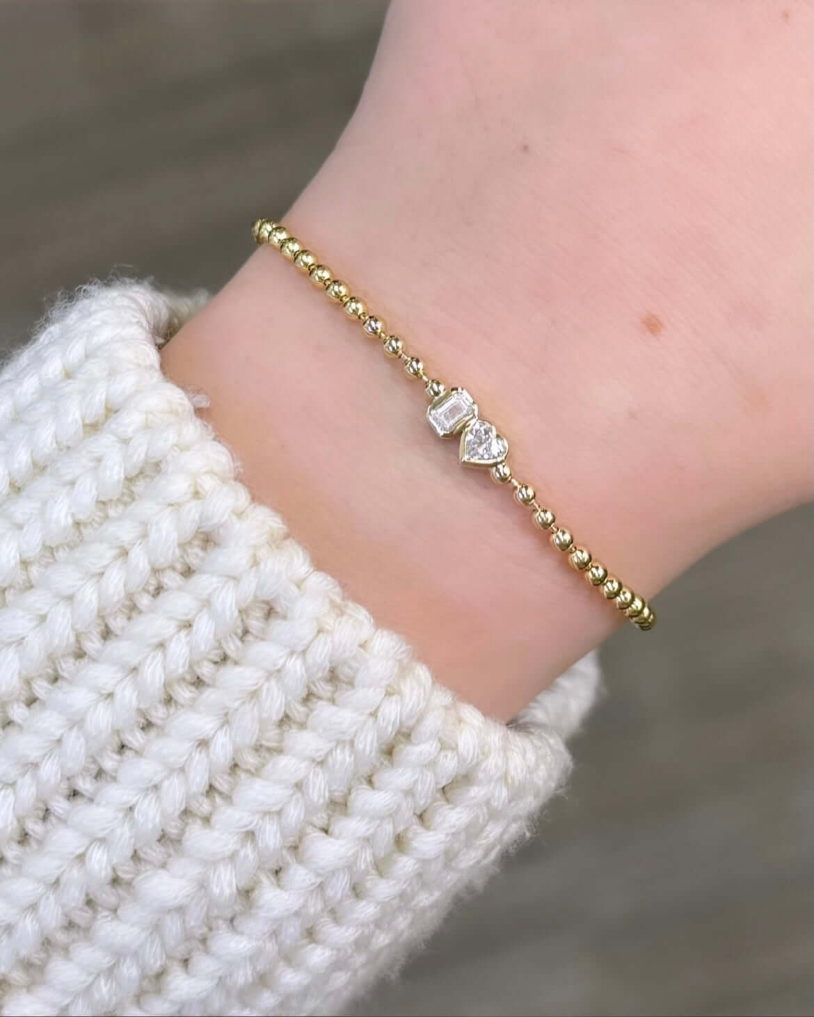 The Emerald & Heart Toi Et Moi Bracelet, from Janet Heller Fine Jewelry, crafted in 14KT gold features a emerald and heart-shaped diamond charm on a beaded bracelet. The emerald and heart are set in bezel settings. The bracelet can be worn on its own or stacked with other bracelets.
