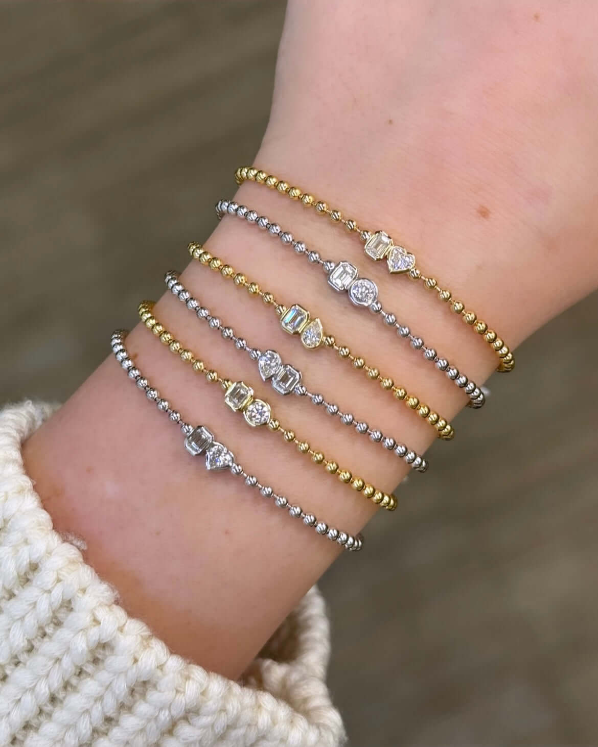 The Emerald & Heart Toi Et Moi Bracelet from Janet Heller Fine Jewelry, is crafted in 14KT gold and features heart and emerald-cut diamonds. The diamonds are 0.15 carats each and are in bezel settings. The bracelet can be worn on its own or stacked with others.