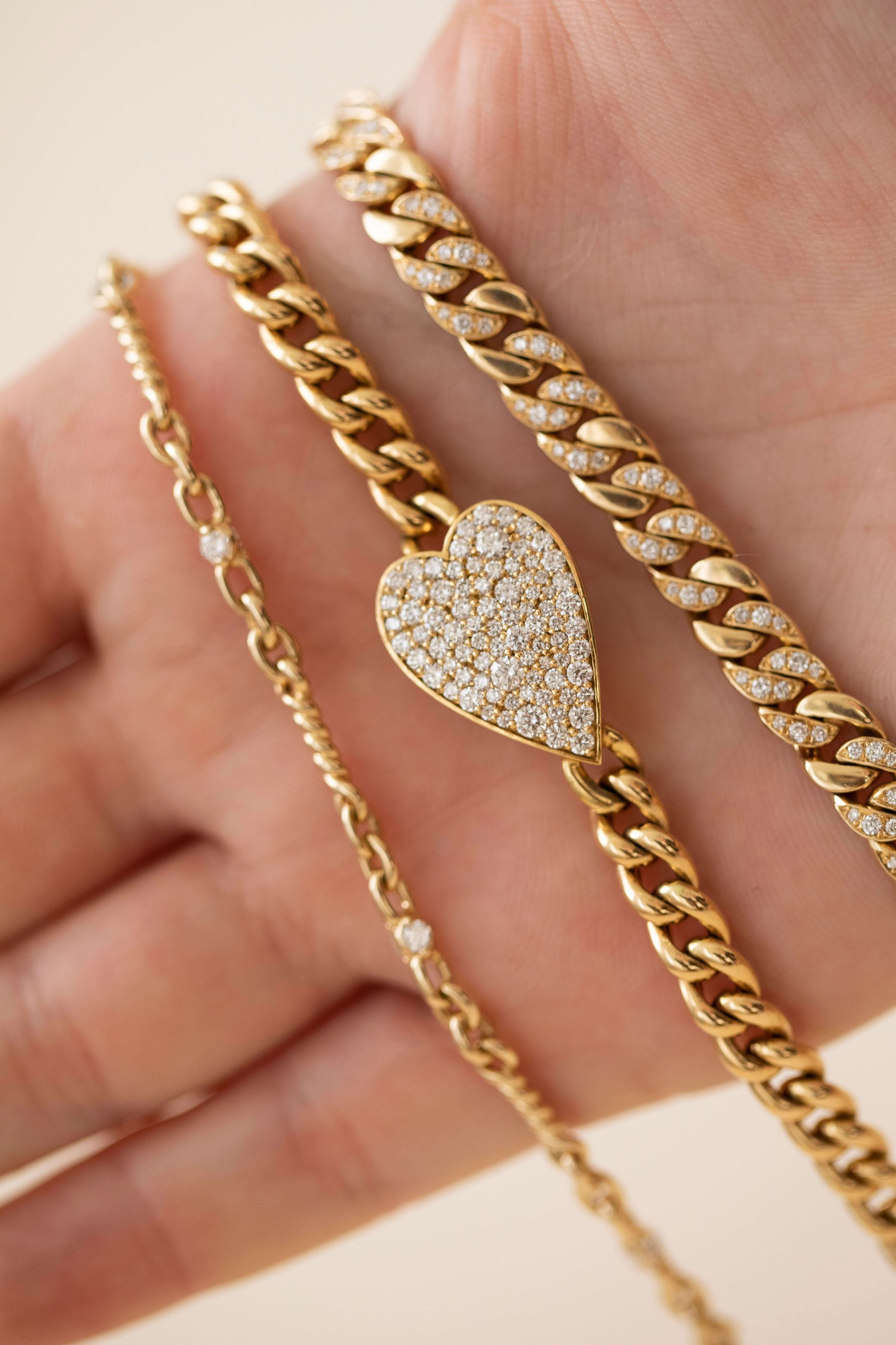 The Cuban Link Diamond Heart Bracelet from Janet Heller Fine Jewelry is crafted in 14KT gold.  The chain features a diamond-encrusted heart-shaped pendant and a smaller diamond heart dangles near the clasp. The diamonds are G-H in color and the clarity is VS.
