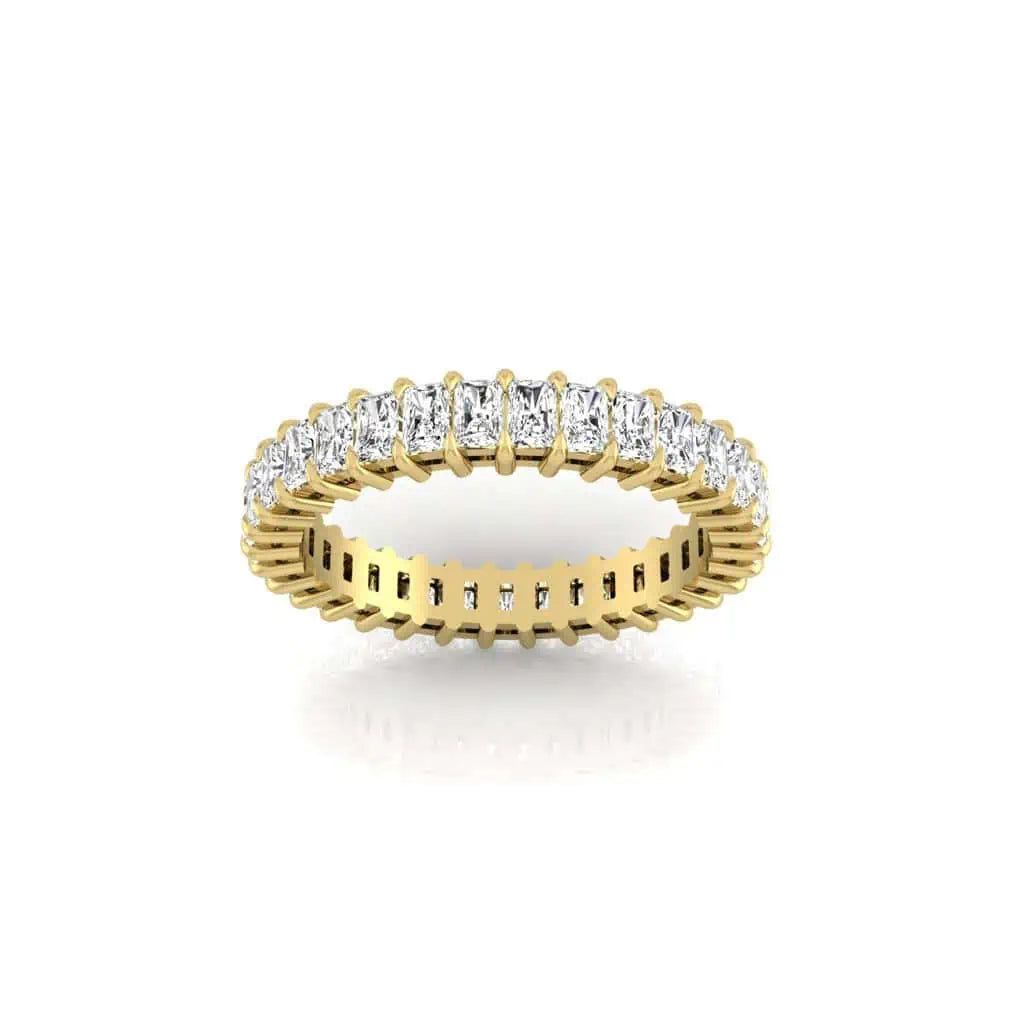 The Full Diamond Eternity Ring, crafted from 18KT gold, showcases a band of rectangular white diamonds with VS clarity and F color. This intricately detailed ring is elegantly displayed on a reflective white surface.
