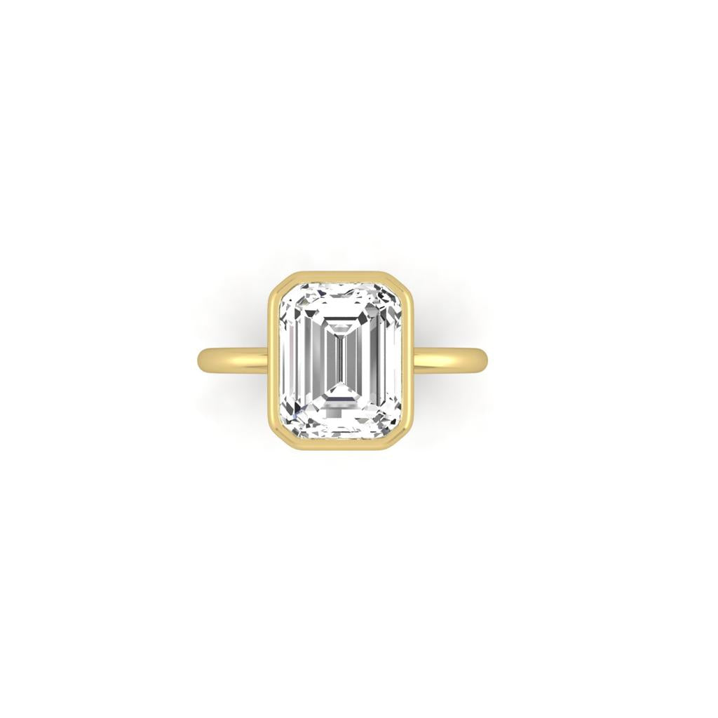 The Classic Bezel ring, in 18KT gold, showcases a large emerald-cut clear gemstone in a classic bezel setting. Its elegant simplicity is accentuated against a white background.