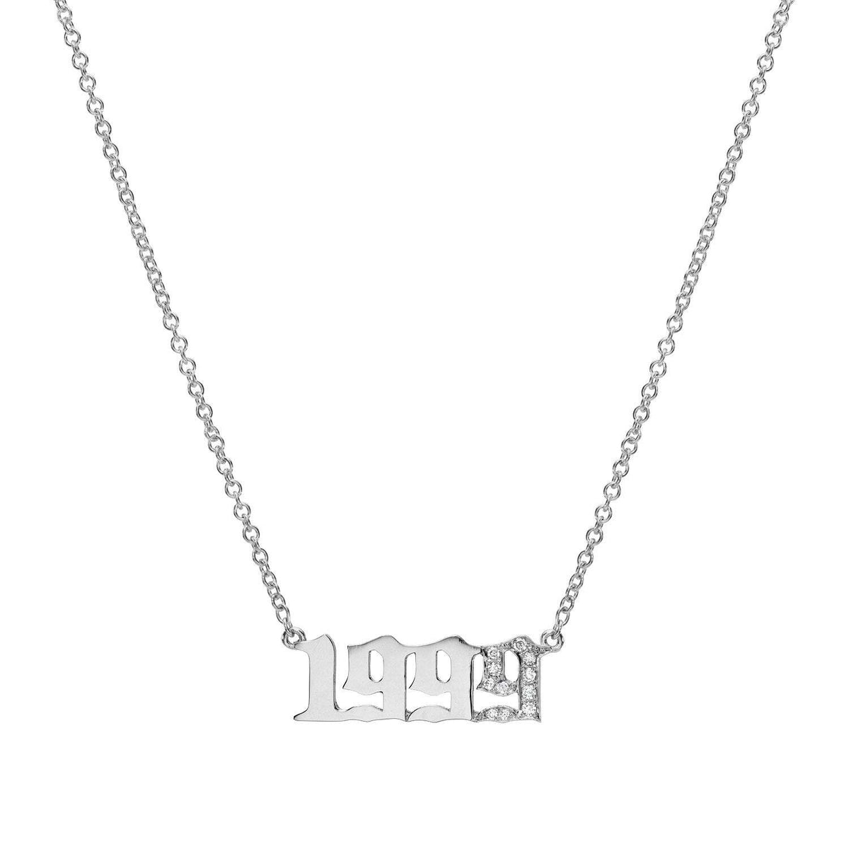 The Diamond Year Necklace is a silver chain necklace featuring a pendant shaped as the year “1999” in a stylized font, with the final “9” encrusted with small, sparkling stones. Isolated on a white background, this unique piece of jewelry makes a striking statement and adds a touch of individuality to any collection.