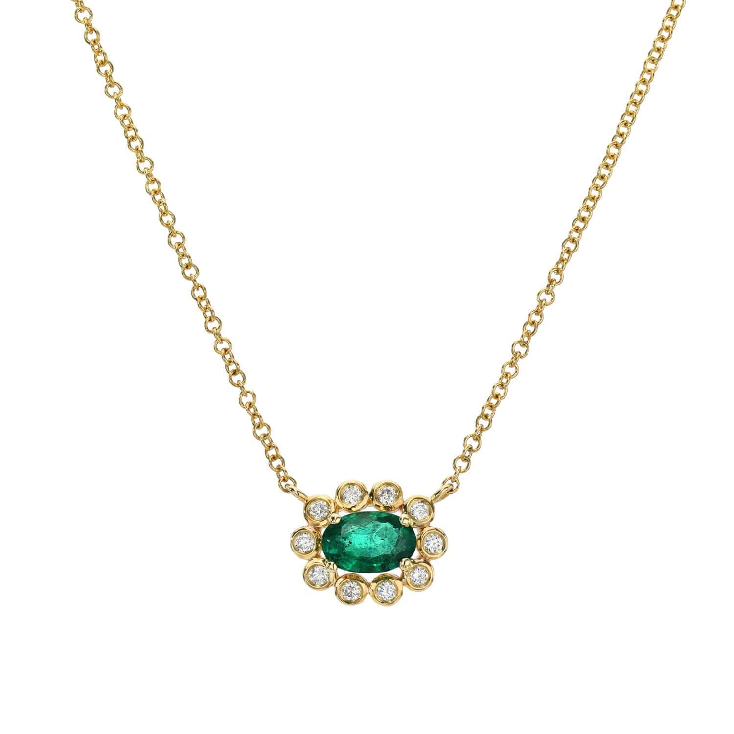 The Scalloped Emerald & Diamond Necklace by Janet Heller Fine Jewelry features an oval emerald encircled by a halo of diamonds in an elegant floral design, hanging on a fine gold chain with personalization options available.