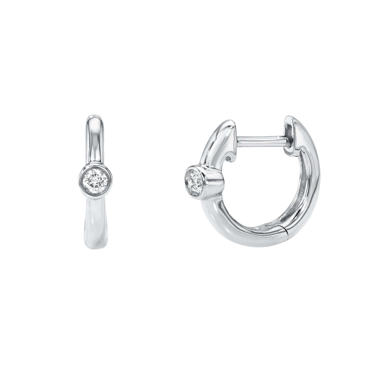The Diamond Axel Huggies are silver hoop earrings featuring a small round diamond at the center of each. They snap together at the back, combining sleek metallic curves with a dazzling sparkle.