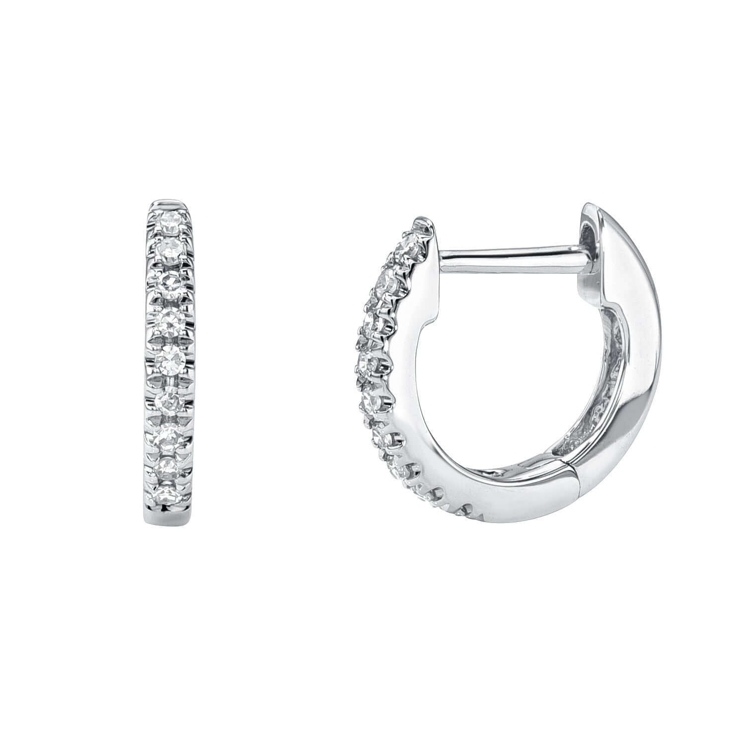 The Mini Diamond Anika Huggies from Janet Heller fine jewelry are small silver hoop earrings, each adorned with a row of sparkling diamonds. One earring is displayed from the front and the other from the side.