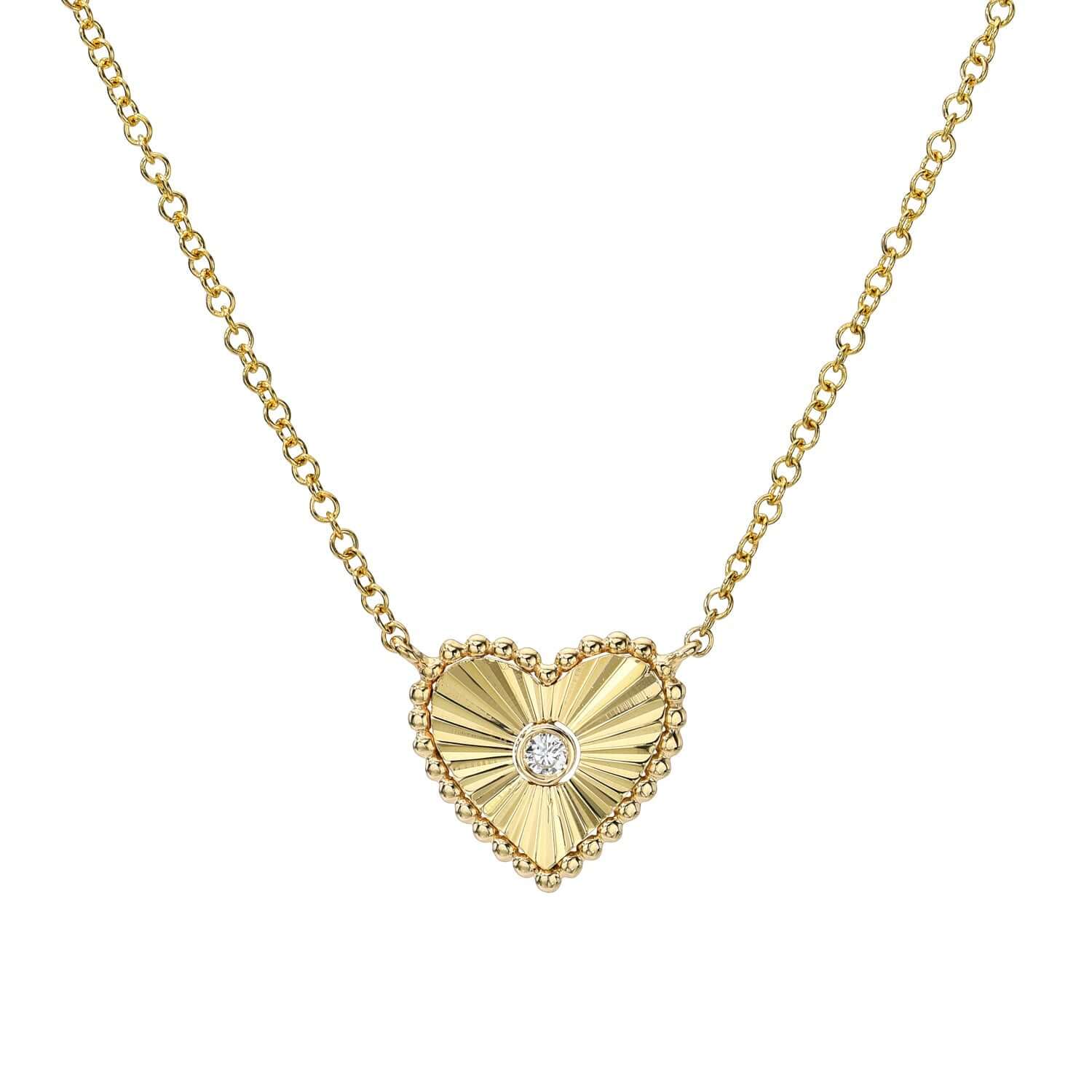 The Mini Diamond Ridge Heart Necklace from Janet Heller Fine Jewelry is crafted in 14KT gold.  The delicate chain features a heart-shaped pendant with a ribbed design, scalloped edges and a diamond in the center.  The necklace can be layered or worn on its own.