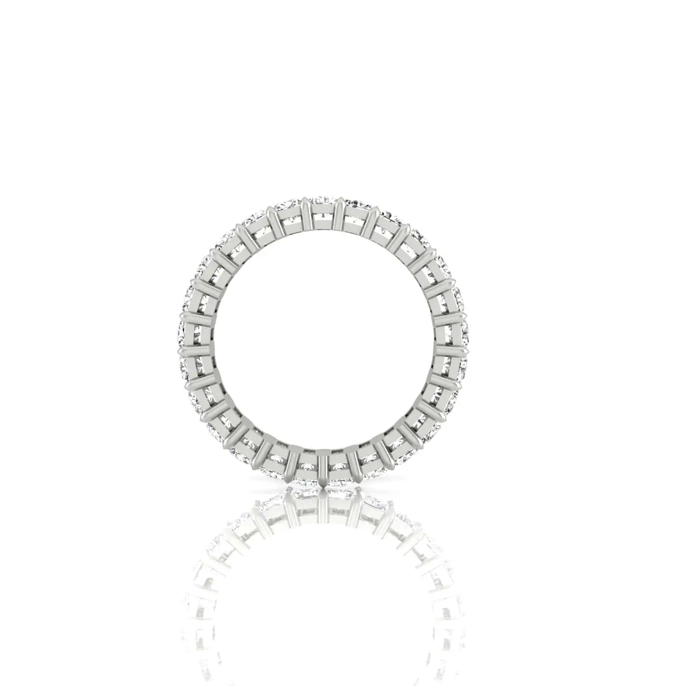 An 18KT gold Full Diamond Eternity Ring with rectangular patterns stands upright on a reflective white surface. Its intricate design and F Color precision create a mirrored effect below, showcasing its stunning craftsmanship.
