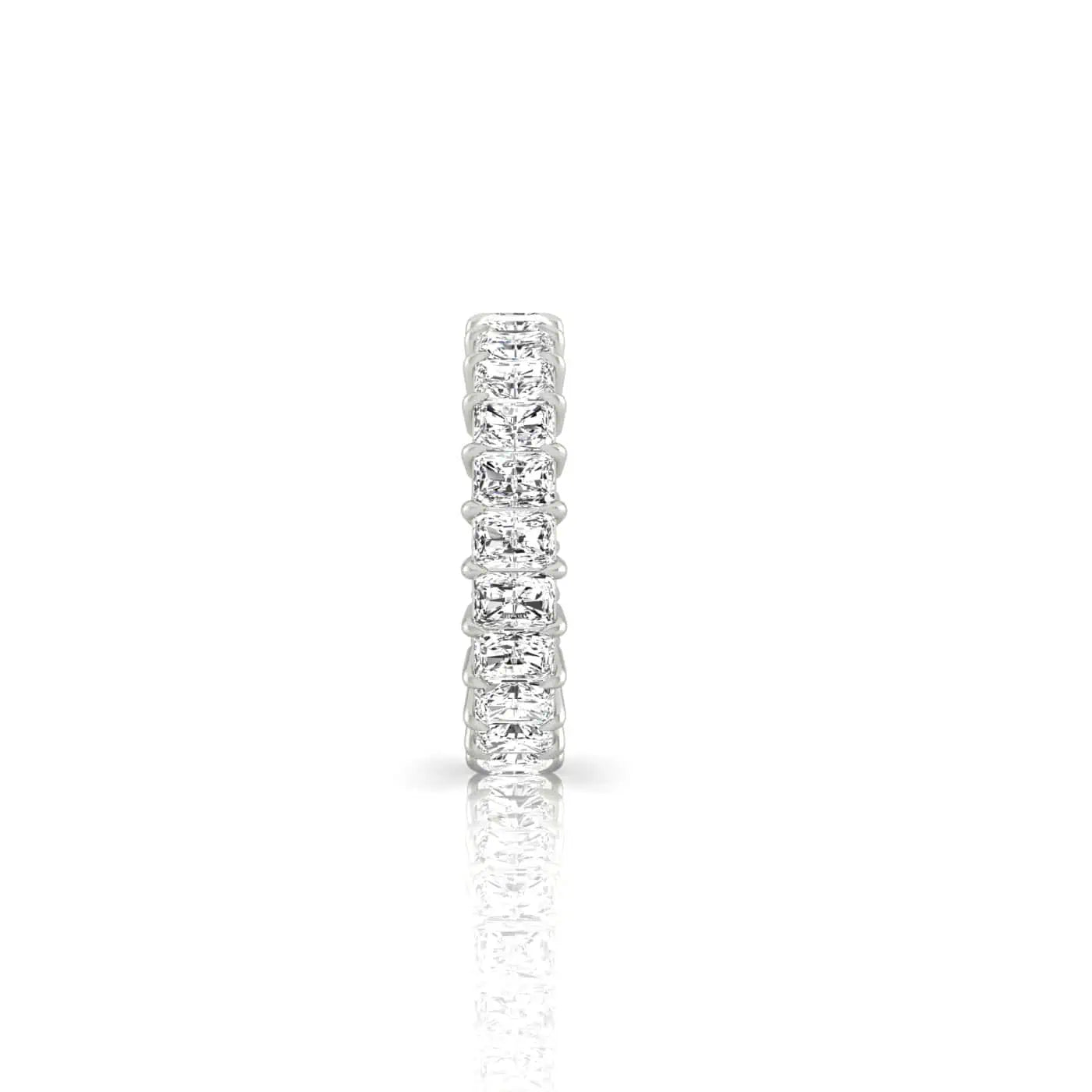 The Full Diamond Eternity Ring, featuring a row of F Color, VS Clarity diamonds, sparkles brilliantly across its silver band against a white background. Its exquisite reflection is artfully captured below.