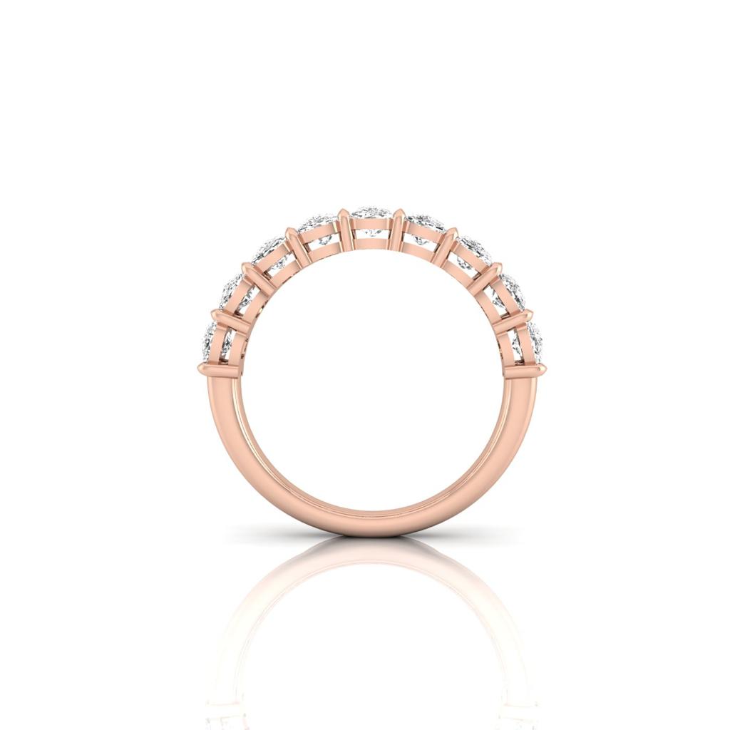 The Half Diamond Eternity Ring is a breathtaking 18KT rose gold band adorned with VS Clarity diamonds. Multiple gemstones beautifully line its top half, elegantly displayed upright against a pristine white background to emphasize its elegant, reflective surface.