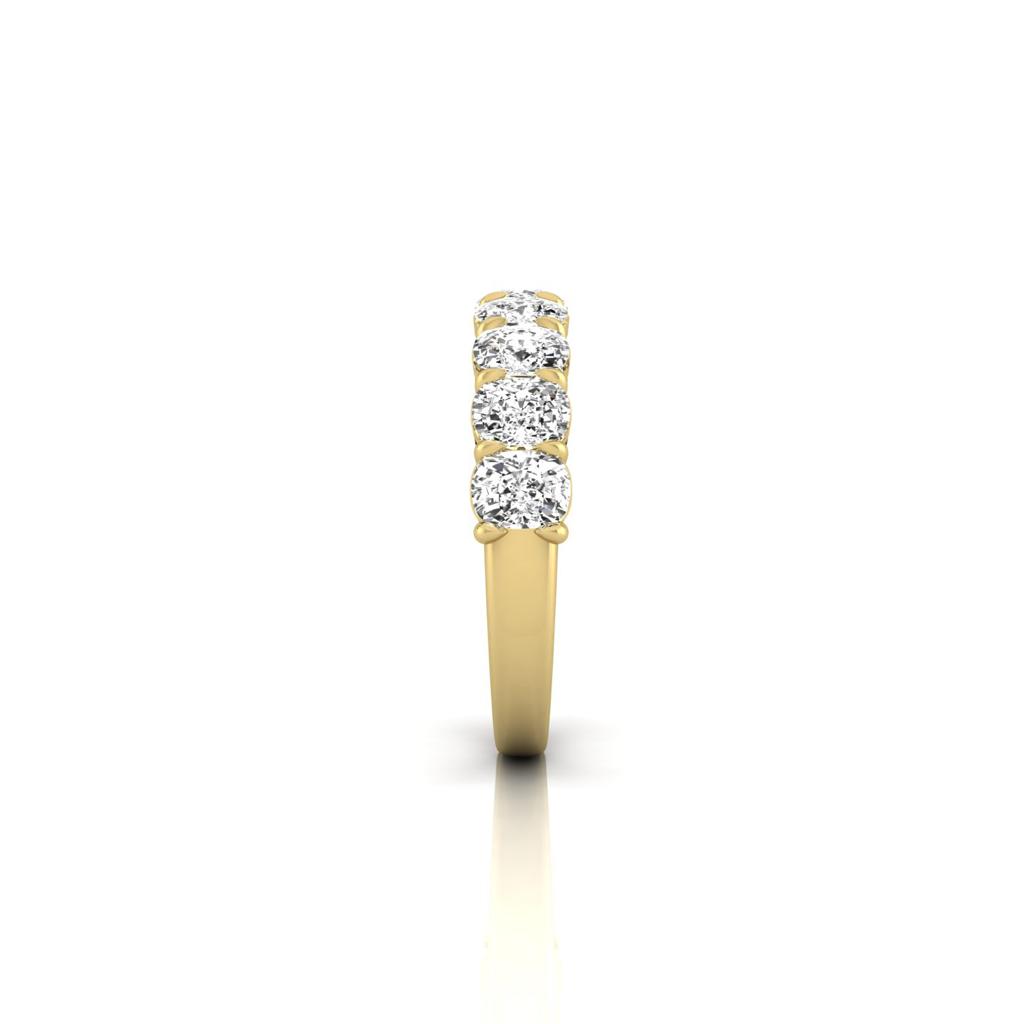 The Half Lab Grown Diamond Eternity Ring, crafted in 18KT gold, showcases five round-cut diamonds set symmetrically across the top. Positioned vertically against a white background, the ring highlights the stones brilliance and the bands sleek elegance.