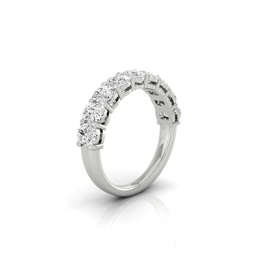 The Half Lab Grown Diamond Eternity Ring, custom-made in silver, features seven small, round sparkling diamonds along the top half. It is displayed on a white background with a subtle reflection underneath, offering exquisite diamond information for discerning buyers.