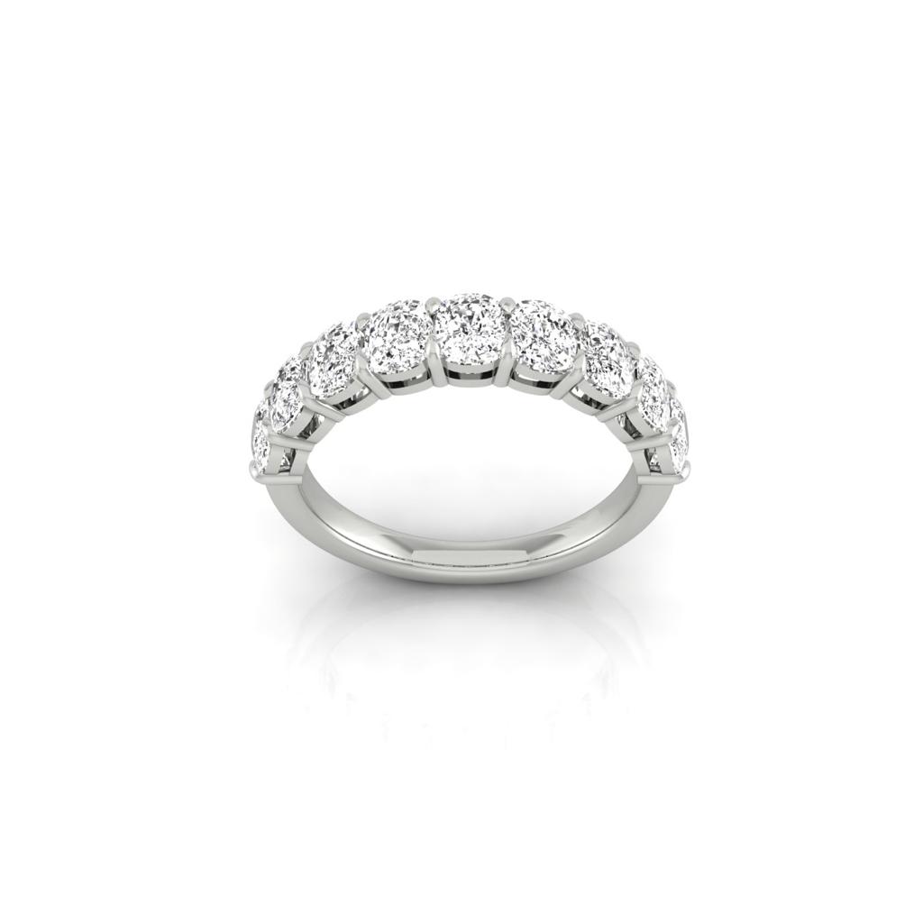 The Half Lab Grown Diamond Eternity Ring, a custom-made silver band encrusted with round diamonds, sparkles on a reflective white surface. Its elegant design and 18KT gold setting beautifully highlight the shimmering stones.