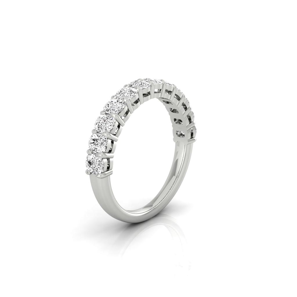 The Half Diamond Eternity Ring boasts a glistening silver band adorned with a half circle of round, sparkling diamonds of VS clarity, elegantly set along the top. Its beautifully displayed on a white reflective surface.