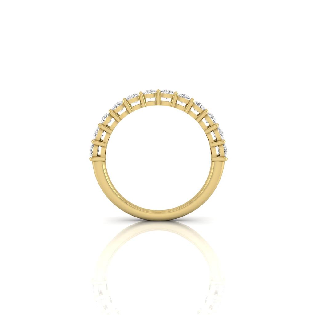 The Half Diamond Eternity Ring showcases a row of VS clarity diamonds set in lustrous 18KT gold. Displayed vertically on a reflective surface, its exquisite design and impeccable craftsmanship stand out against a pristine white background.