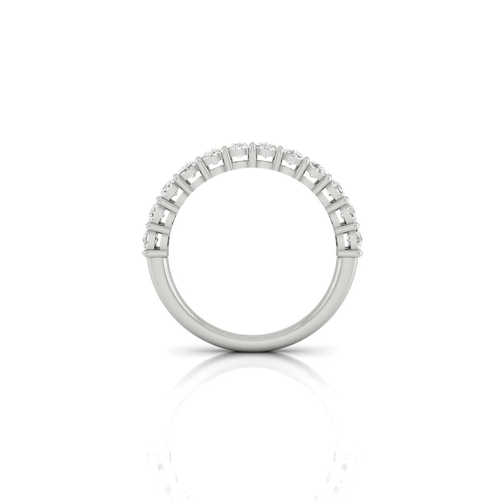 A side view of the Half Lab Grown Diamond Eternity Ring reveals small, sparkling diamonds elegantly set in a custom-made design. Displayed on a reflective white surface, the ring showcases its luxurious 18KT gold craftsmanship with an elegant and minimalist style.