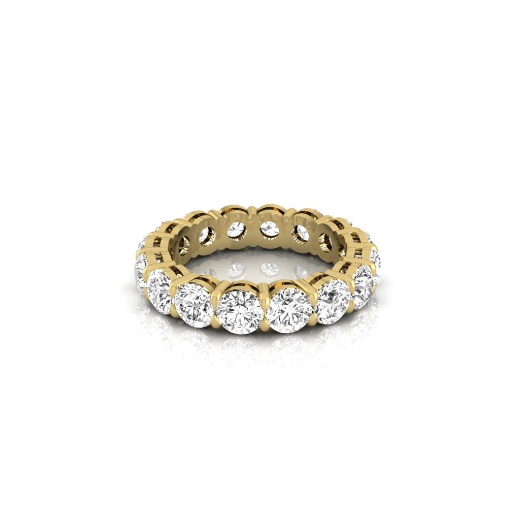 The Full Lab Grown Diamond Eternity Ring features an 18KT gold band with round diamonds, each in a four-prong setting. The F Color VS Clarity stones are elegantly arranged on a scalloped, openwork band, highlighted against a plain white backdrop.