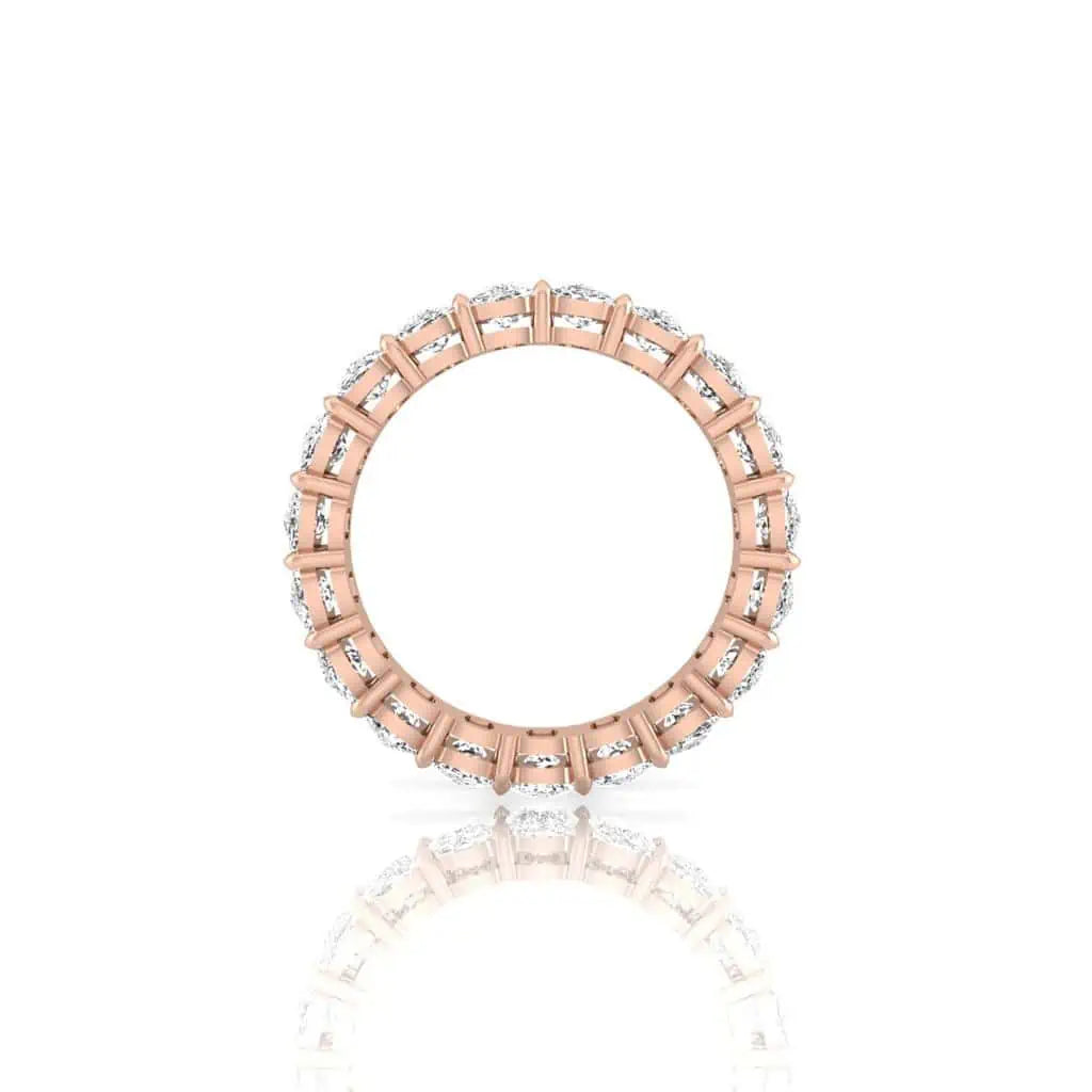 The Full Diamond Eternity Ring, made of 18KT rose gold, showcases a circle of VS Clarity and F Color diamonds. Set against a white background, its vertical position allows its shimmering reflection to enhance its sparkling loop.