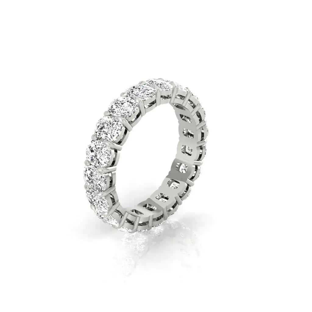 The Full Lab Grown Diamond Eternity Ring, crafted in 18KT gold, features a silver band with a continuous row of round diamonds set in prongs. Displayed at an angle against a white background, its elegant and symmetrical design shines brightly with F Color and VS Clarity enhancement.