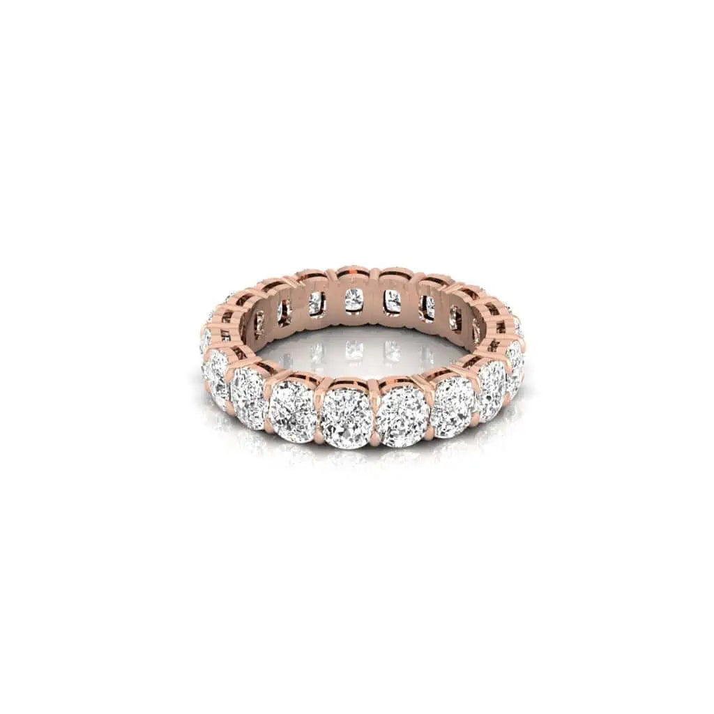 The Full Diamond Eternity Ring is an 18KT rose gold ring adorned with F color round-cut diamonds of VS clarity, encircling the entire band, displayed on a reflective white surface.