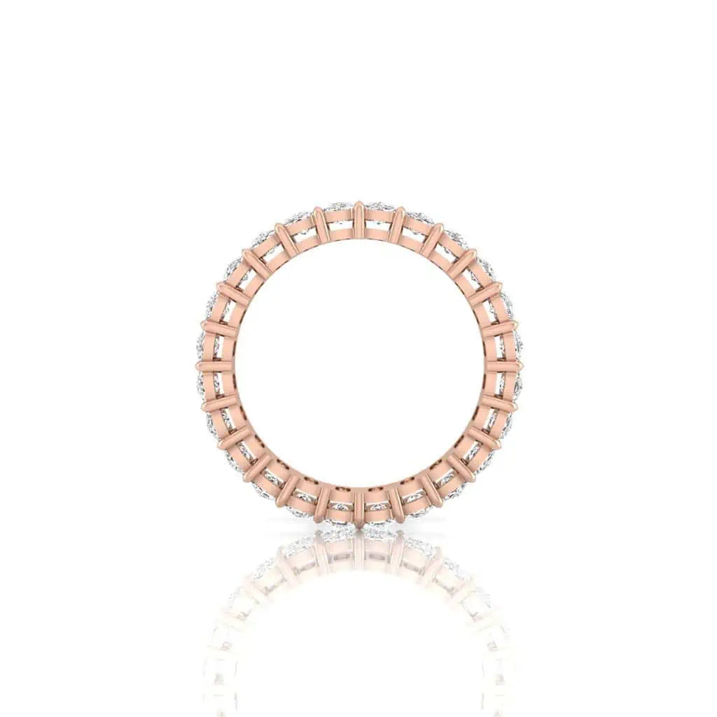 The Full Diamond Eternity Ring is crafted in 18KT rose gold, featuring F Color round diamonds of VS Clarity encircling the band, set against a white reflective background.