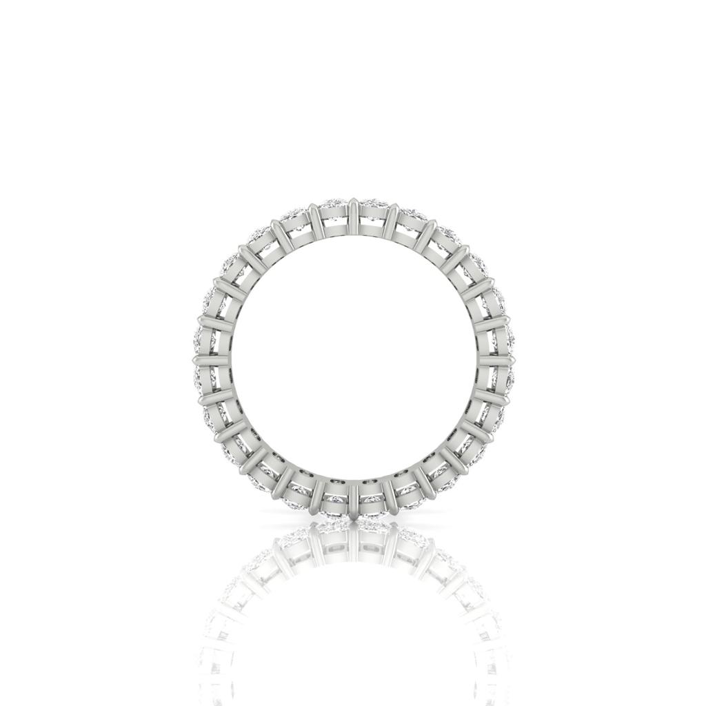The Full Lab Grown Diamond Eternity Ring is an elegant piece, designed in 18KT gold with a silver circular band featuring alternating square and round settings. Each setting holds a sparkling gemstone, beautifully mirrored on the white surface below.