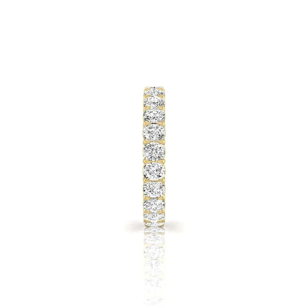 The Full Diamond Eternity Ring is a stunning 18KT gold piece featuring a row of F Color, VS Clarity diamonds uniform in size for a seamless shimmer. The diamonds are set around the entire band and displayed vertically against a white background.