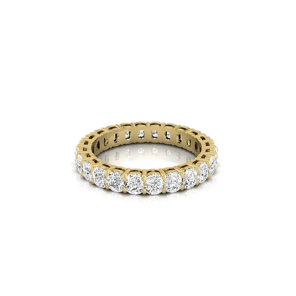 The Full Diamond Eternity Ring, crafted in 18KT gold, features a continuous row of round, sparkling diamonds with VS clarity and F color. It is set against a plain white background to highlight its luxurious and elegant design.