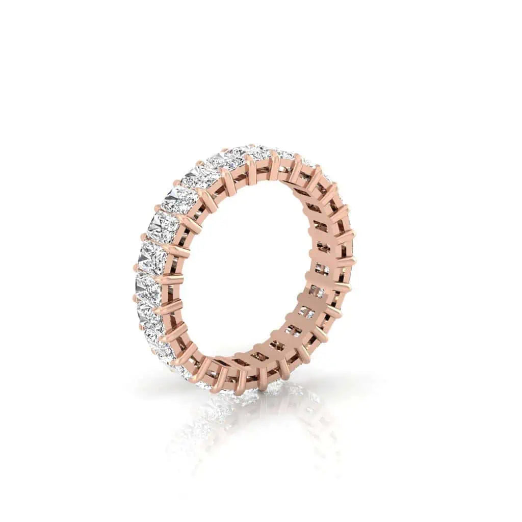 The Full Diamond Eternity Ring is an 18KT rose gold ring with a continuous circle of F color and VS clarity white gemstones in prong settings, evenly spaced around the band.
