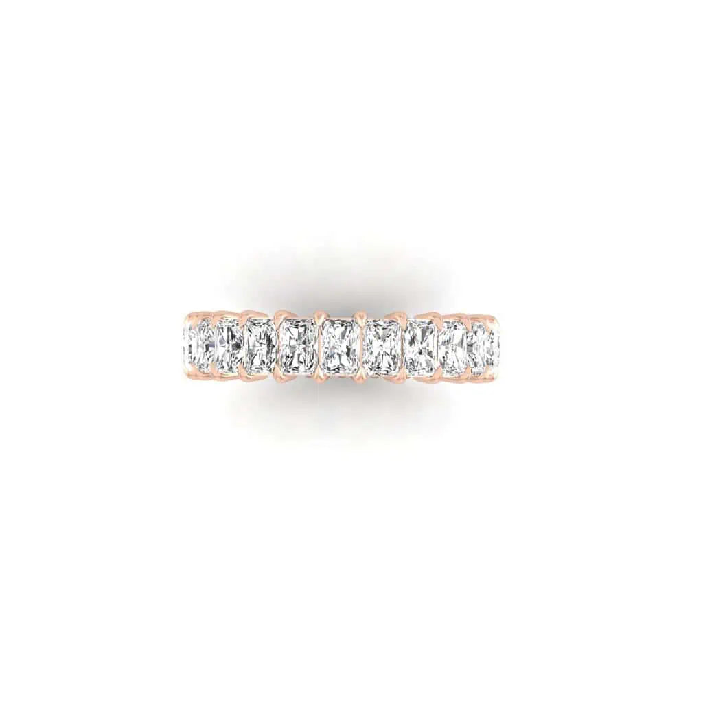 The Full Diamond Eternity Ring is an 18KT rose gold band with a continuous row of rectangular, F color, VS clarity diamonds. A plain white background highlights each diamonds sparkle and elegance.