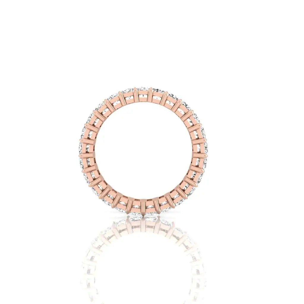 The Full Diamond Eternity Ring, featuring a 18KT rose gold band adorned with F color, VS clarity diamonds forming a complete circle, is elegantly displayed on a white background with its reflection visible below.