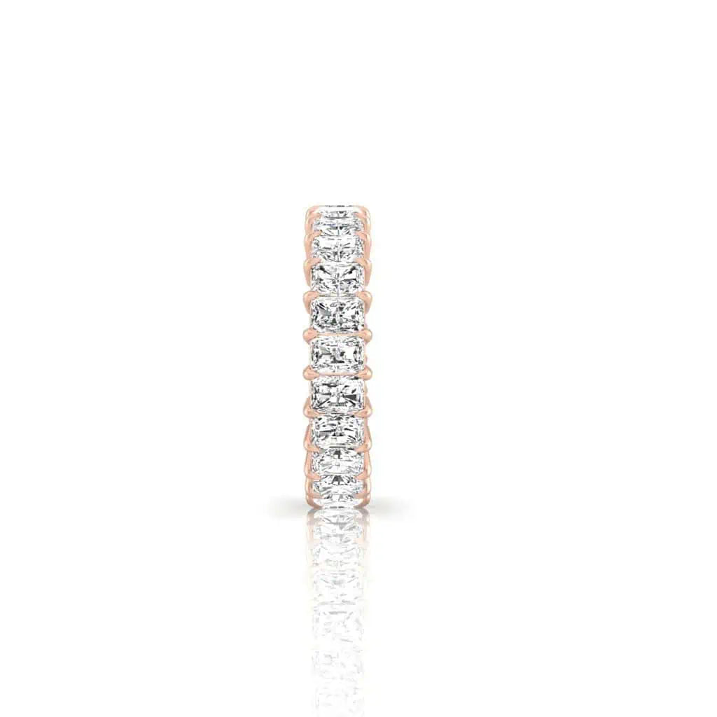 The Full Diamond Eternity Ring, crafted in 18KT rose gold and featuring a row of dazzling F Color VS Clarity diamonds, is elegantly displayed against a white background for a luxurious effect.